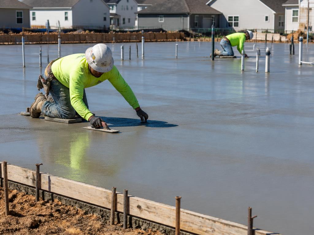 Workers finishing a freshly poured concrete slab on a building site
